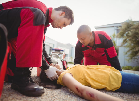 Paramedics examining injured woman on street