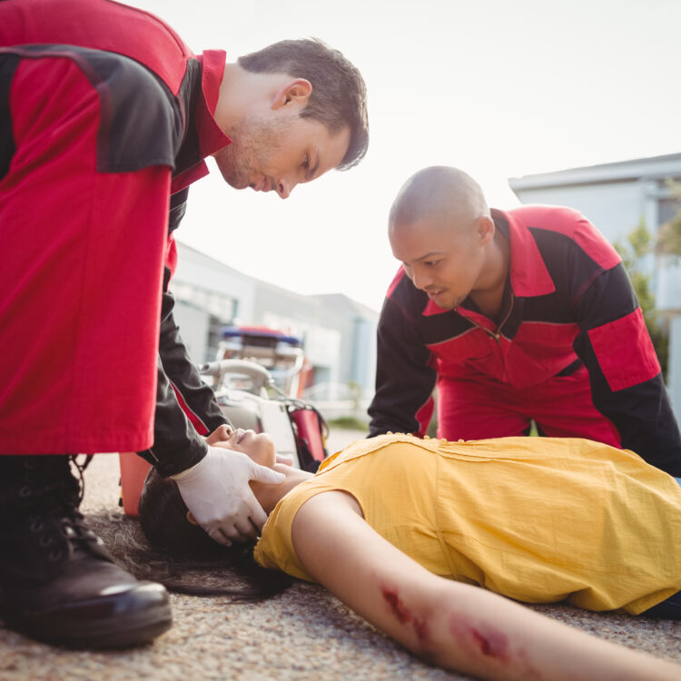 Paramedics examining injured woman on street